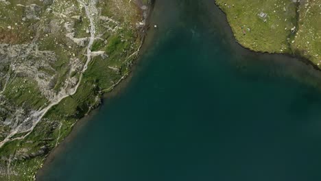 bird's eye view of a beautiful lake with a waterfall in the swiss alps