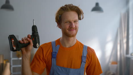 Cheerful man posing with screwdriver in new apartment during home repair.