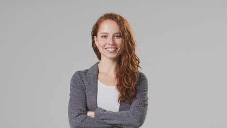 Studio-Portrait-Of-Smiling-Young-Businesswoman-Folding-Arms-Against-Plain-Background