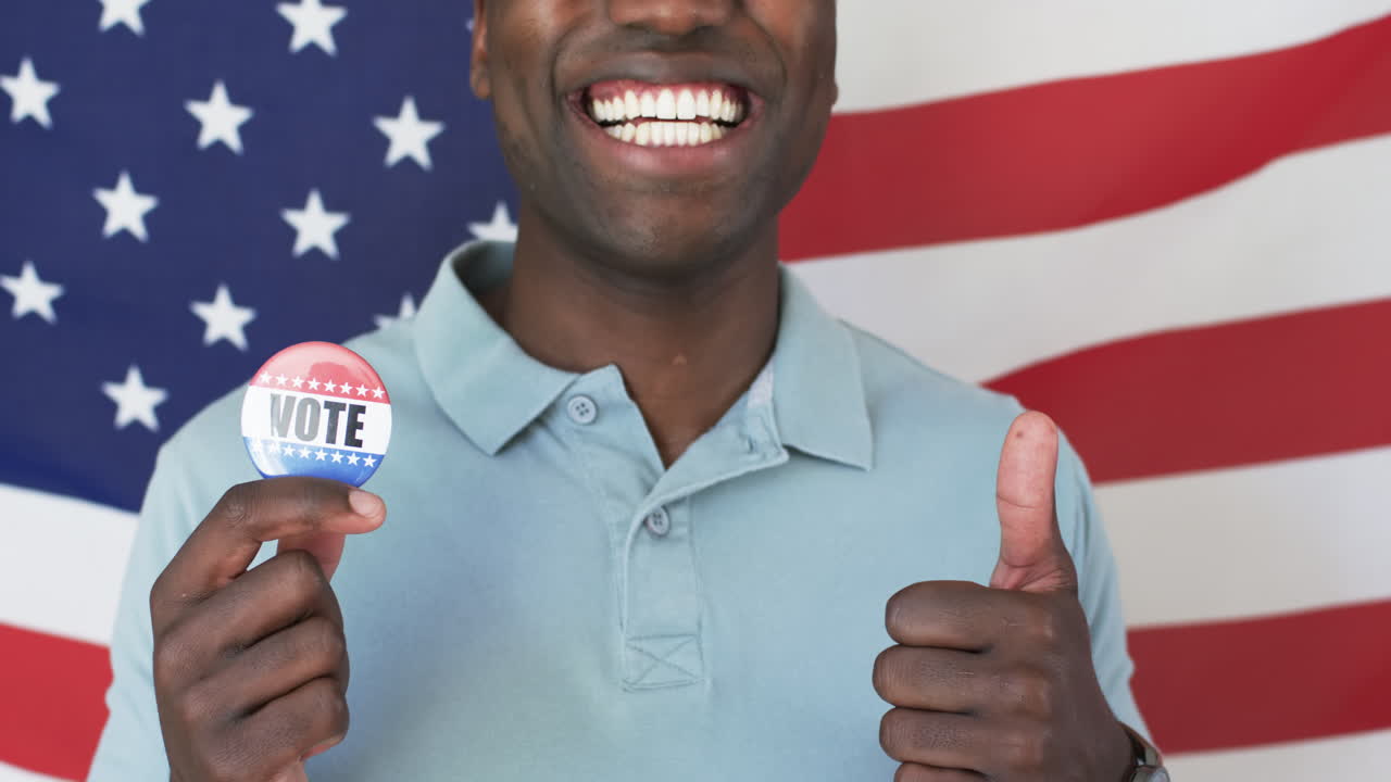 A cheerful African American man shows a voters badge