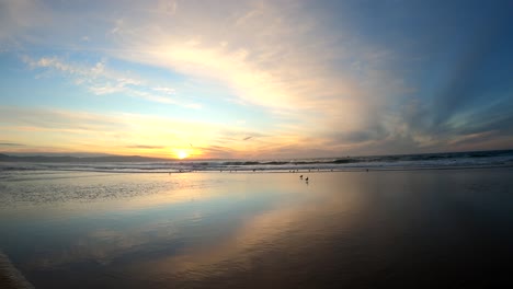 Cielo-De-Puesta-De-Sol-Y-Nubes-Dramáticas-Que-Se-Reflejan-En-La-Arena-Mojada-Durante-La-Marea-Baja-En-El-Parque-Estatal-De-Fort-Ord,-California