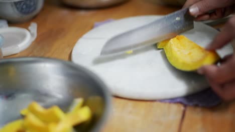 Raw-piece-of-pumpkin-cut-using-knife-of-marble-chopping-block,-filmed-as-close-up-in-slow-motion-style