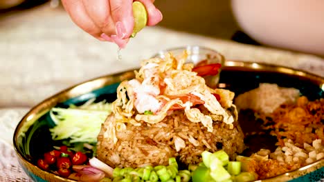 hand garnishing shrimp paste fried rice dish