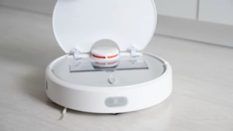 woman opens robot vacuum cleaner show container with rubbish