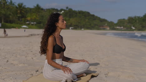 una mujer joven meditando en la playa.