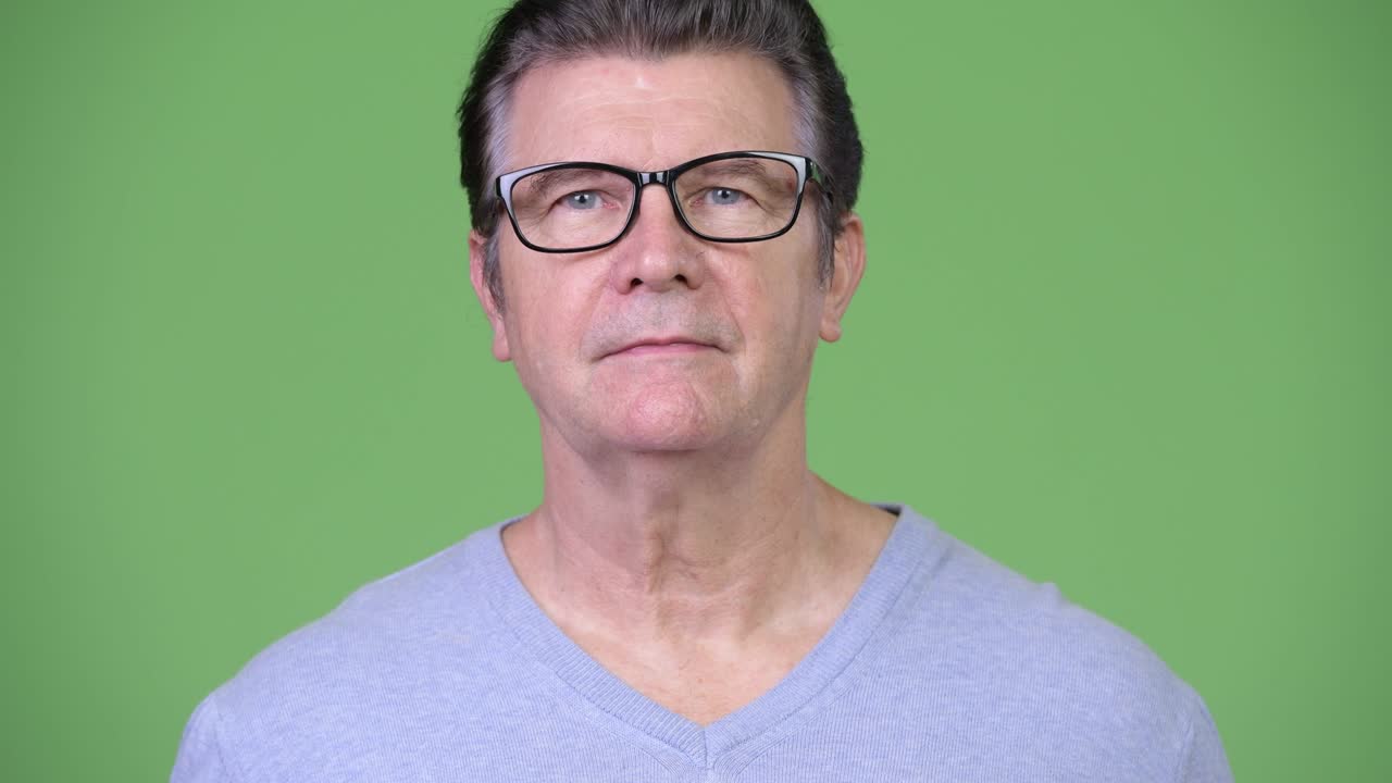 Uomo anziano affascinante con gli occhiali su sfondo verde