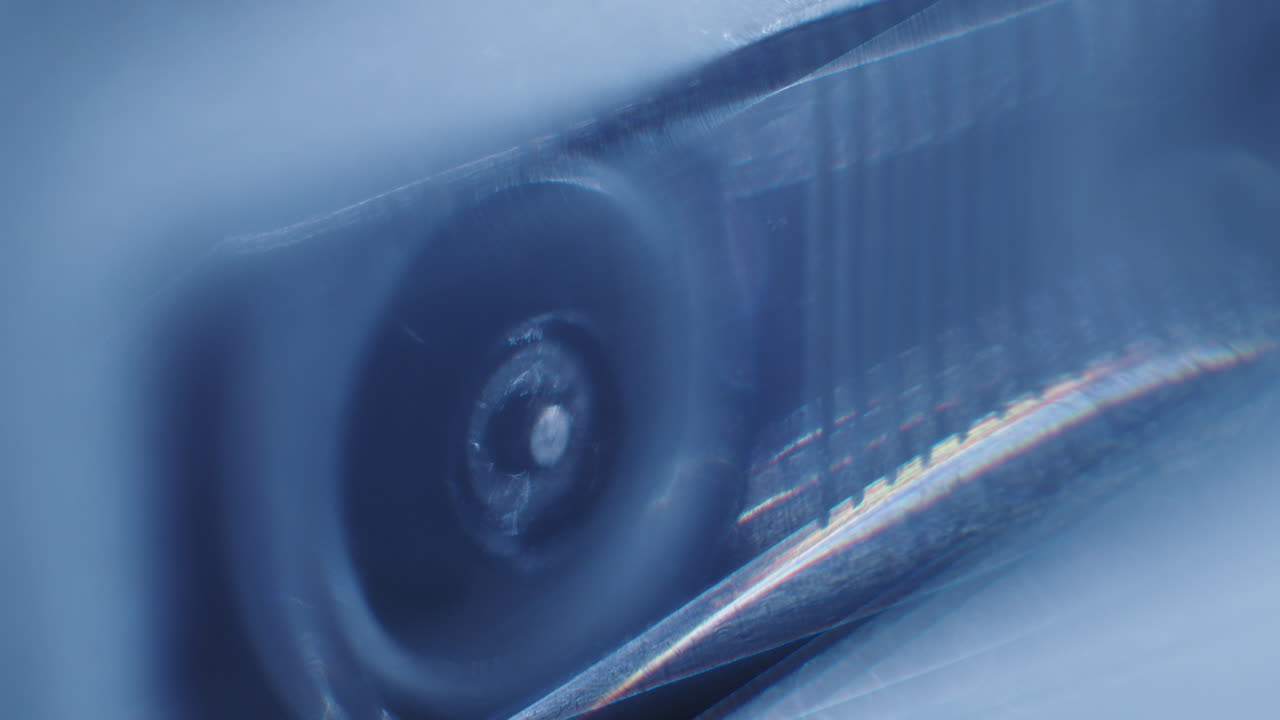 플라스틱 창 뒤에서 돌아가는 마이크로 카세트 레코더 릴의 클로즈업