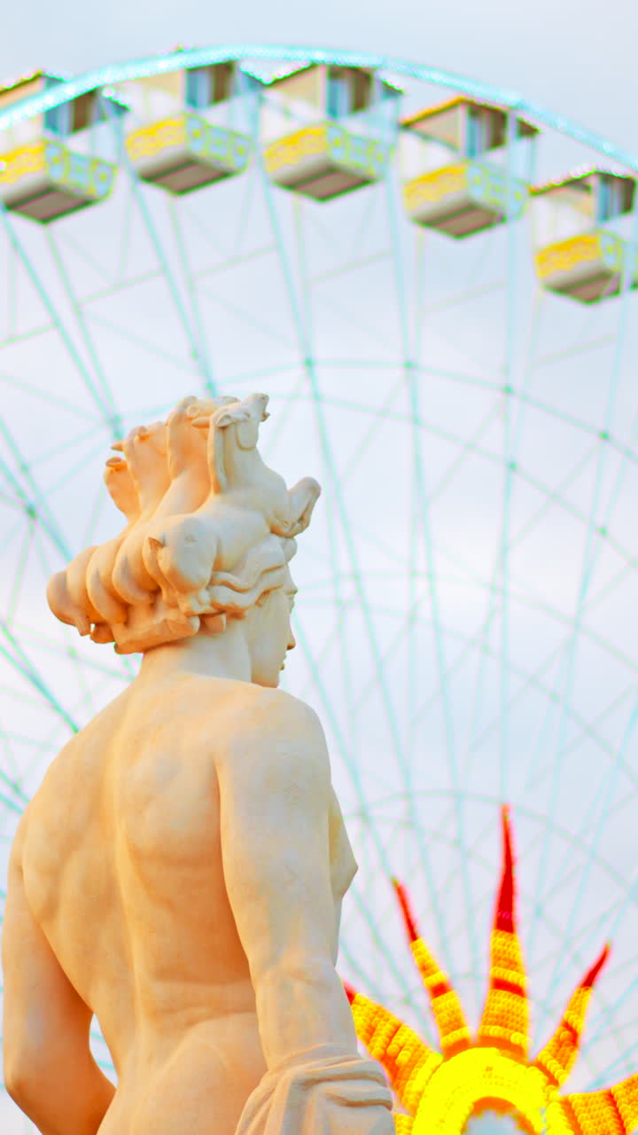 Nice, France - December 8, 2024: Apollo statue in the Fontaine du Soleil at Place Massena with a ferris wheel on the background. Vertical