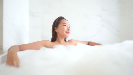 asian woman relaxing in bubble bath in luxury bathroom