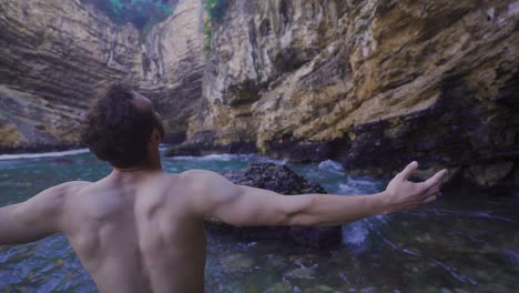 el hombre libre levanta los brazos mirando los acantilados en el mar.