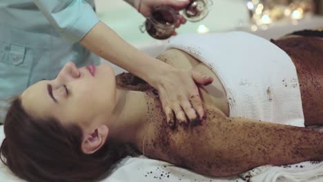 woman receiving a coffee scrub treatment at a spa