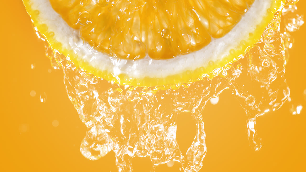 Fetta d'arancia schizzata d'acqua al rallentatore e in macro su sfondo arancione