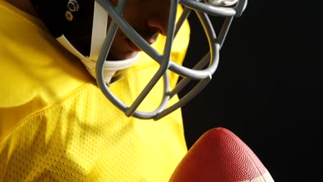 american football player holding ball against black background 4k