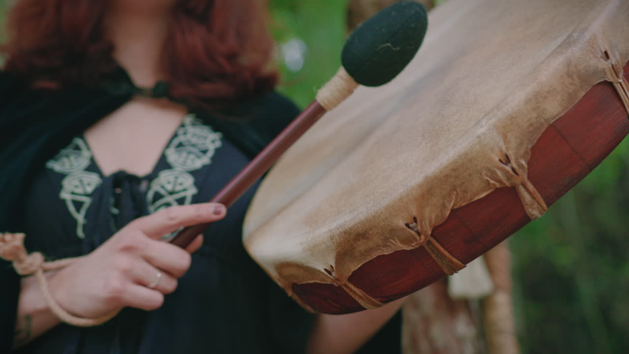 chica druida en un bosque tocando un tambor chamánico detalle de ángulo bajo disparo de cerca