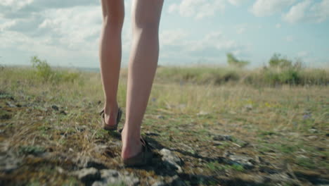 women walking in sandals on a dry field, following handheld