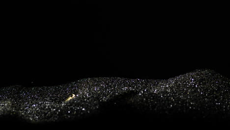 falling golden 9mm bullets on silver black sand with black background, close up slowmotion