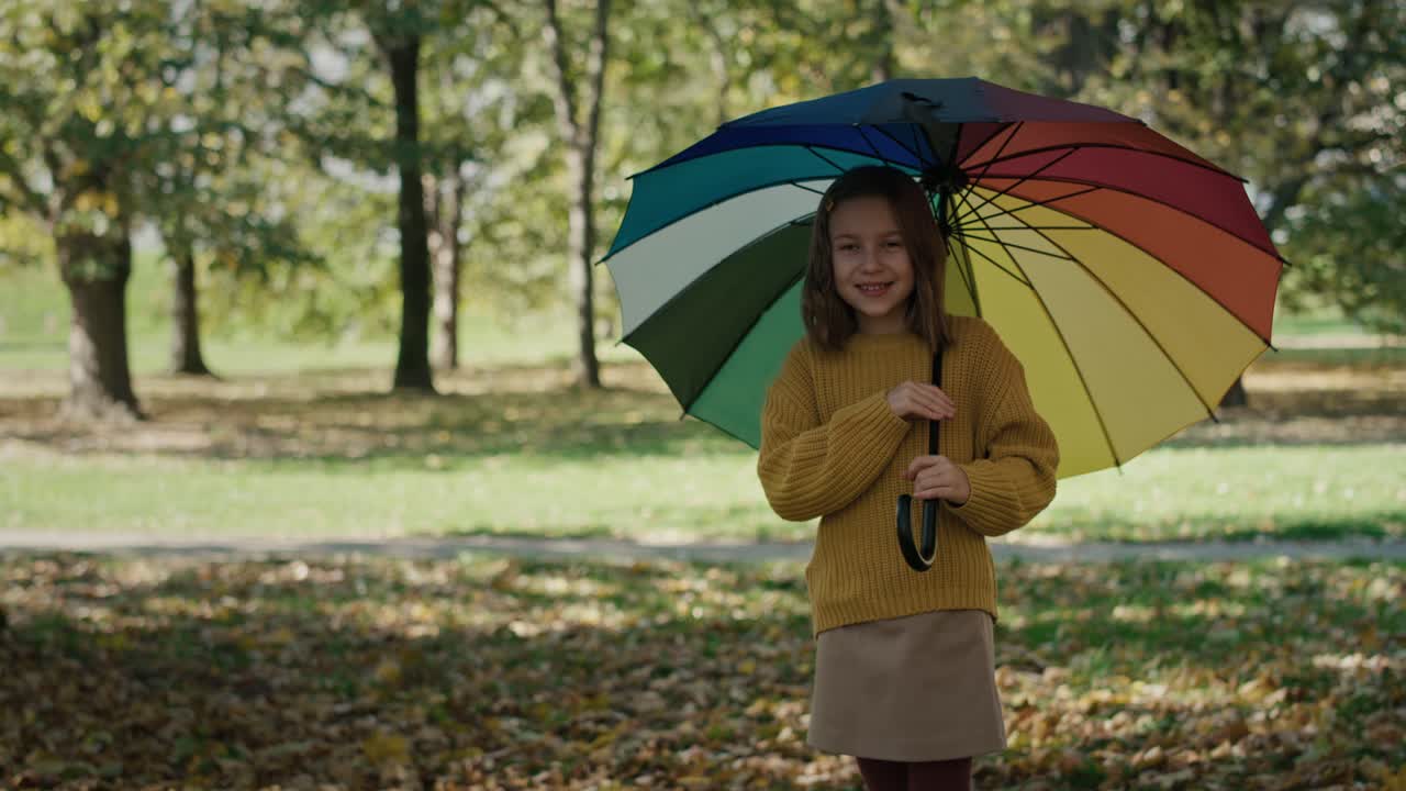 가을에 다채로운 우산과 함께 공원에서 서 있는 작은 소녀.