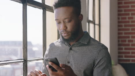 portrait young african american man using smartphone drinking coffee at home browsing messages networking texting social media sharing lifestyle online enjoying relaxing in modern apartment close up