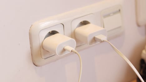 close up of hand unplugging power cord into socket to save energy