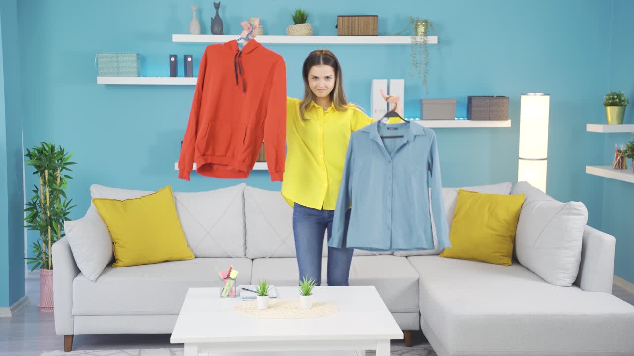 행복한 젊은 소녀가 춤을 추고 카메라를 보고 옷을 선택합니다.