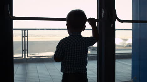 young boy looking through window in the airport