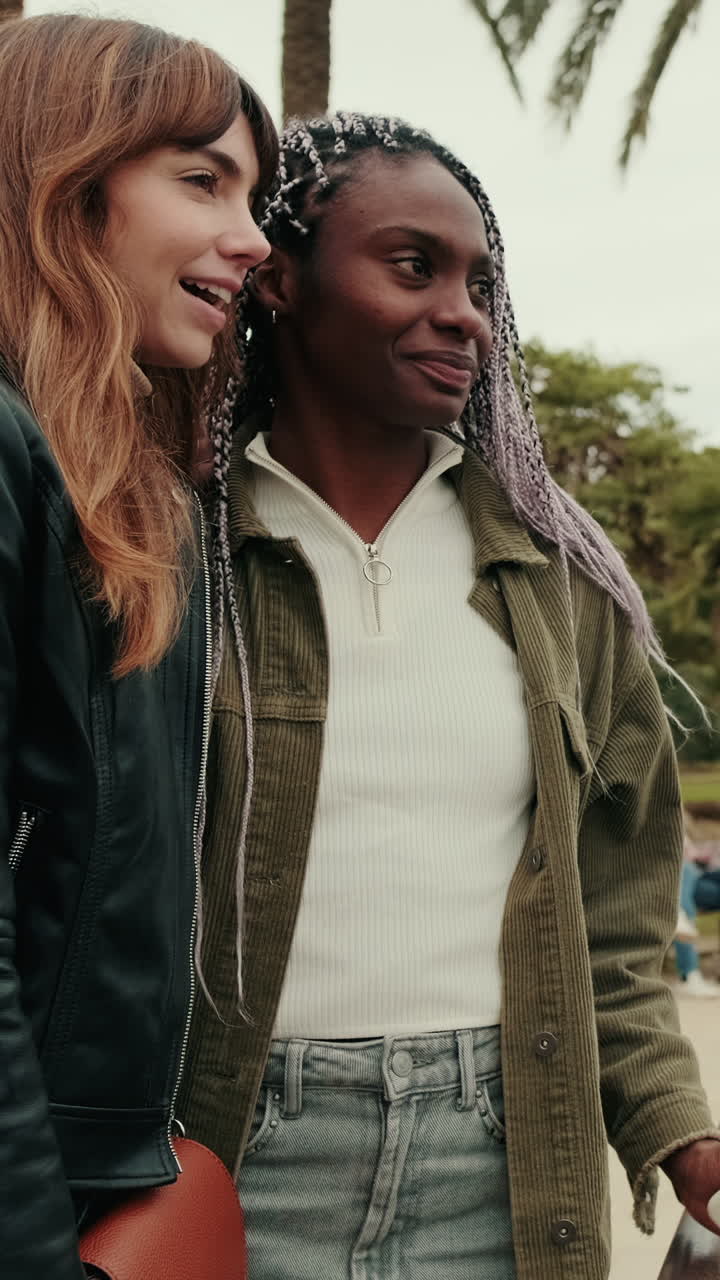 Two Young Diverse Women Talking and Smiling in a Park