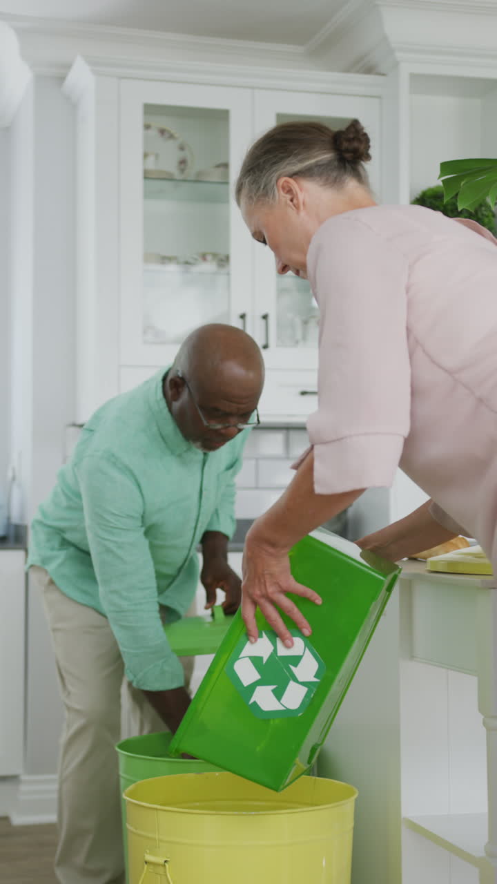 video vertical de una feliz pareja de ancianos diversos segregando los desechos