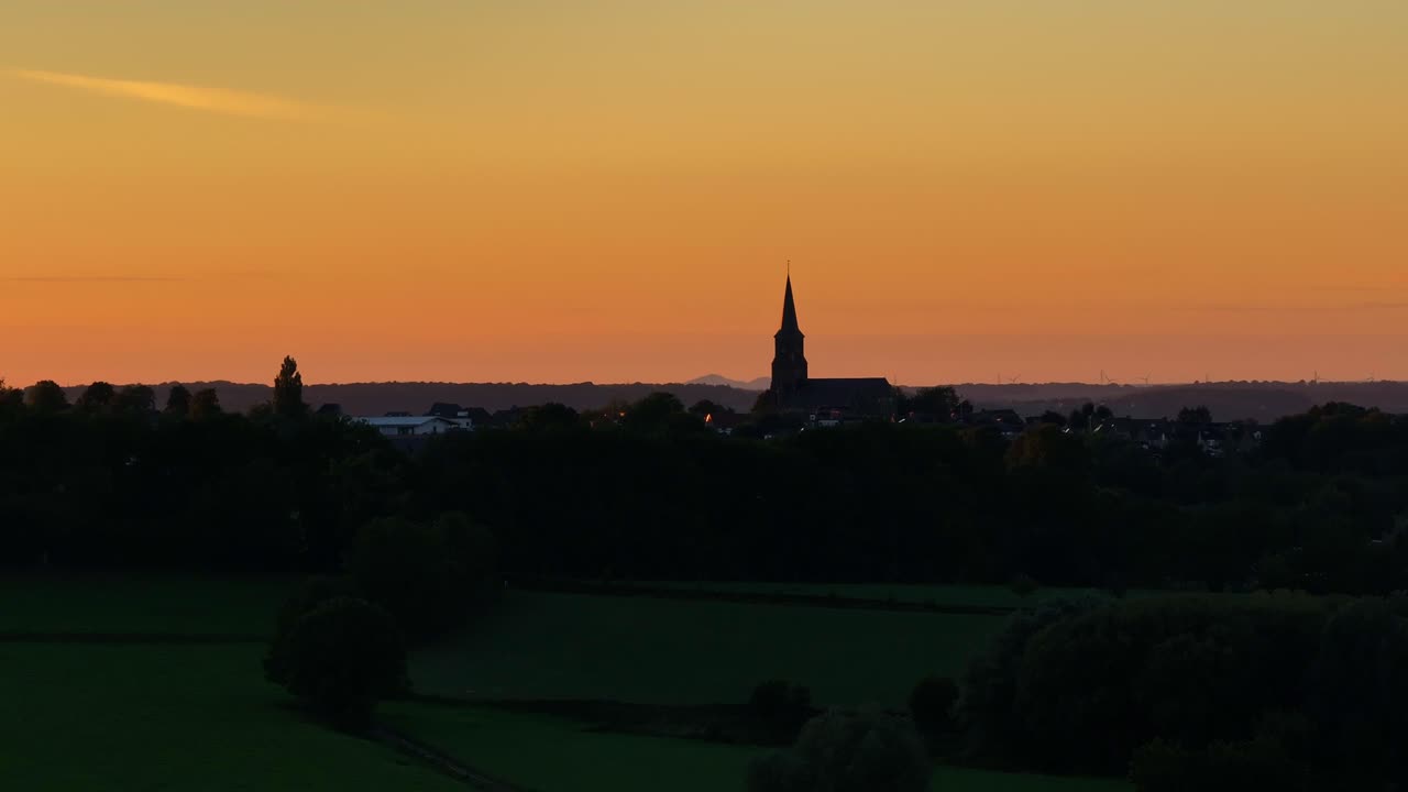 아래로 내려오는  ⁇ 빛으로 조명된 높은 교회 첨탑이 지배하는 지평선