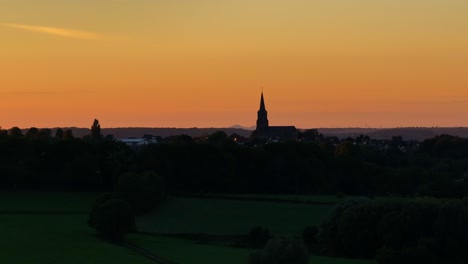 horizon dominated by tall church spire illuminated by descending sunlight