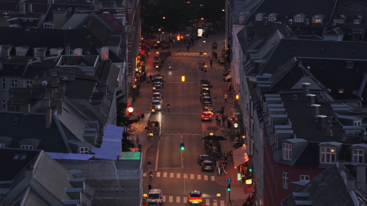 Aerial drone view of a lively street illuminated by cars, bicycles, and pedestrians in Norrebro