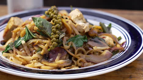 Traditional-plated-tofu-Pad-Kee-Mao-plated-with-fresh-basil-leaves-and-sprig-of-green-peppercorns,-slider-close-up-4K