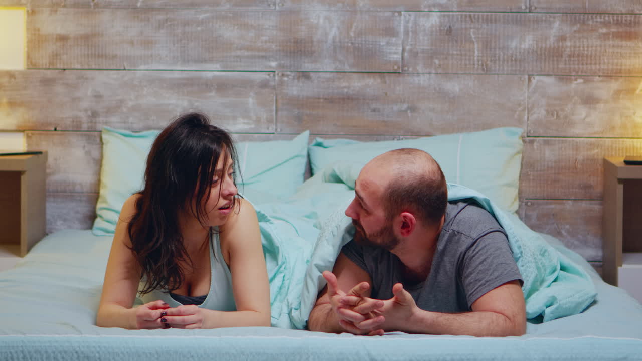 una pareja joven acostada en la cama con pijama.