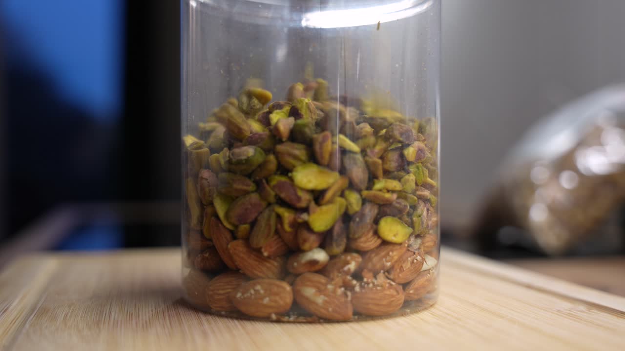 Macro shot of mixed nuts filling plastic jar. Healthy vegan snack