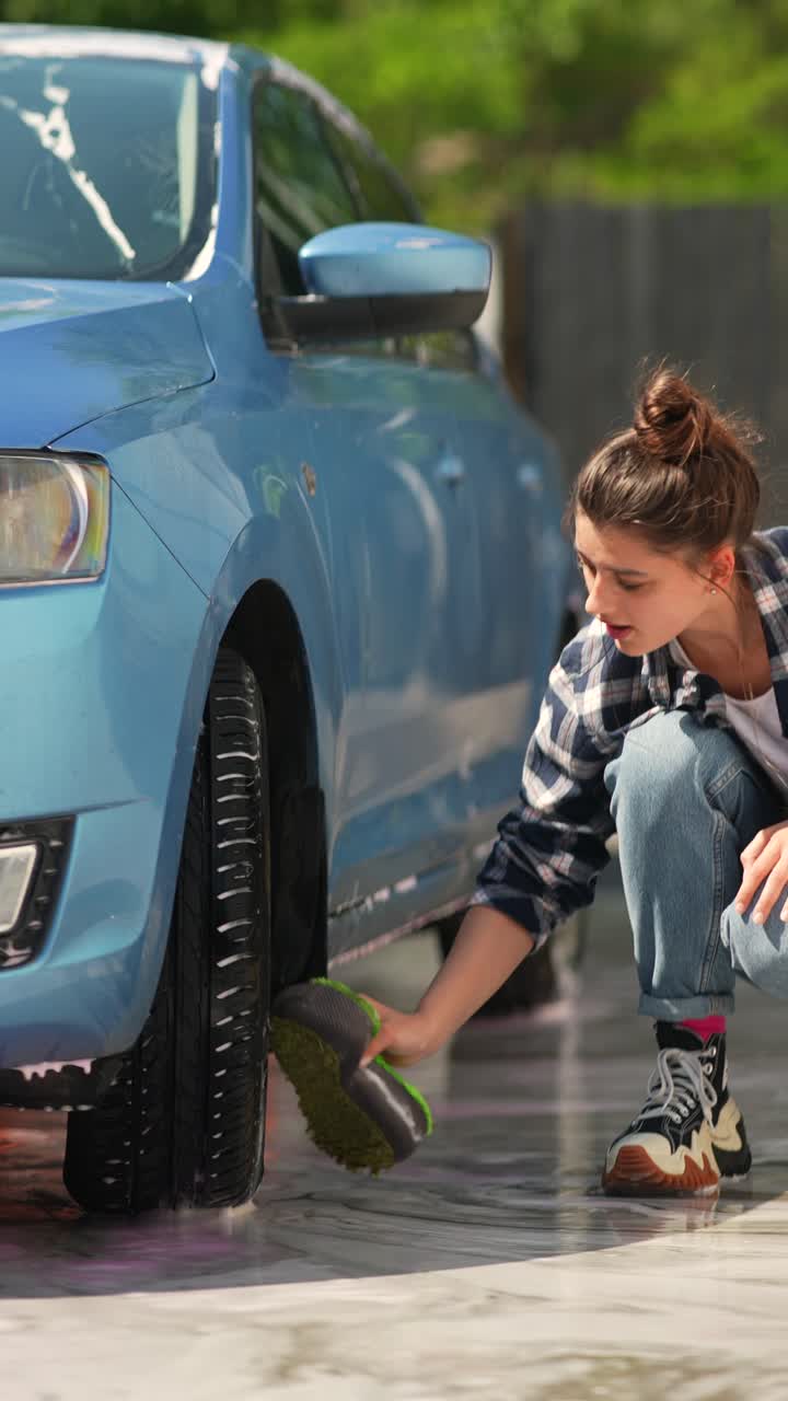 mujer lavando un coche azul en un lavado de coches