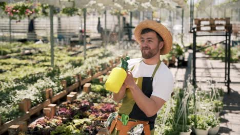 Jardinero-Macho-Adulto-Alegre-En-Aguas-De-Delantal-Con-Un-Rociador-Todo-Lo-Que-Ve