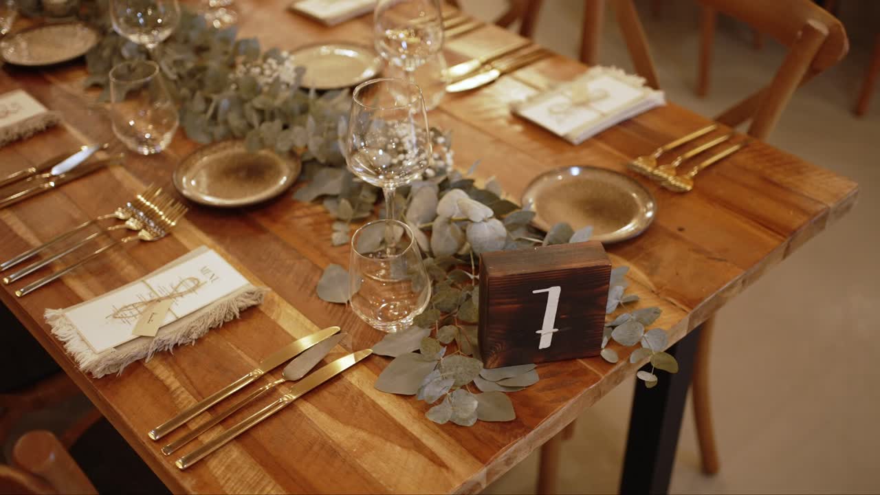 Wooden wedding table set with gold cutlery and eucalyptus centerpiece