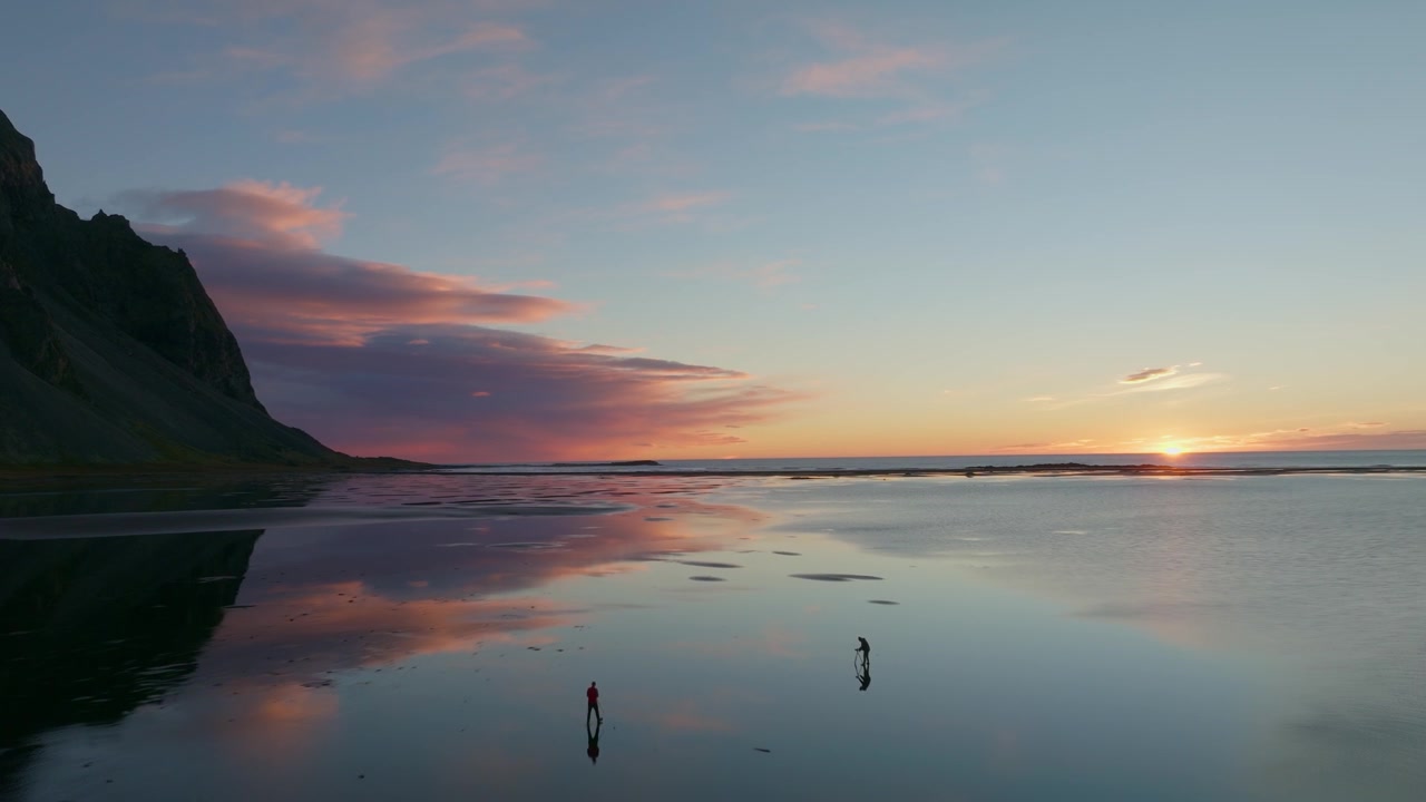 Luchtfoto met drone van zonsopgang boven de getijdenvlakten van Stokksnes onder Vestrahorn, met kalme reflecties, kustmoerassen en kleurrijk ochtendlicht langs de zuidoostkust van IJsland