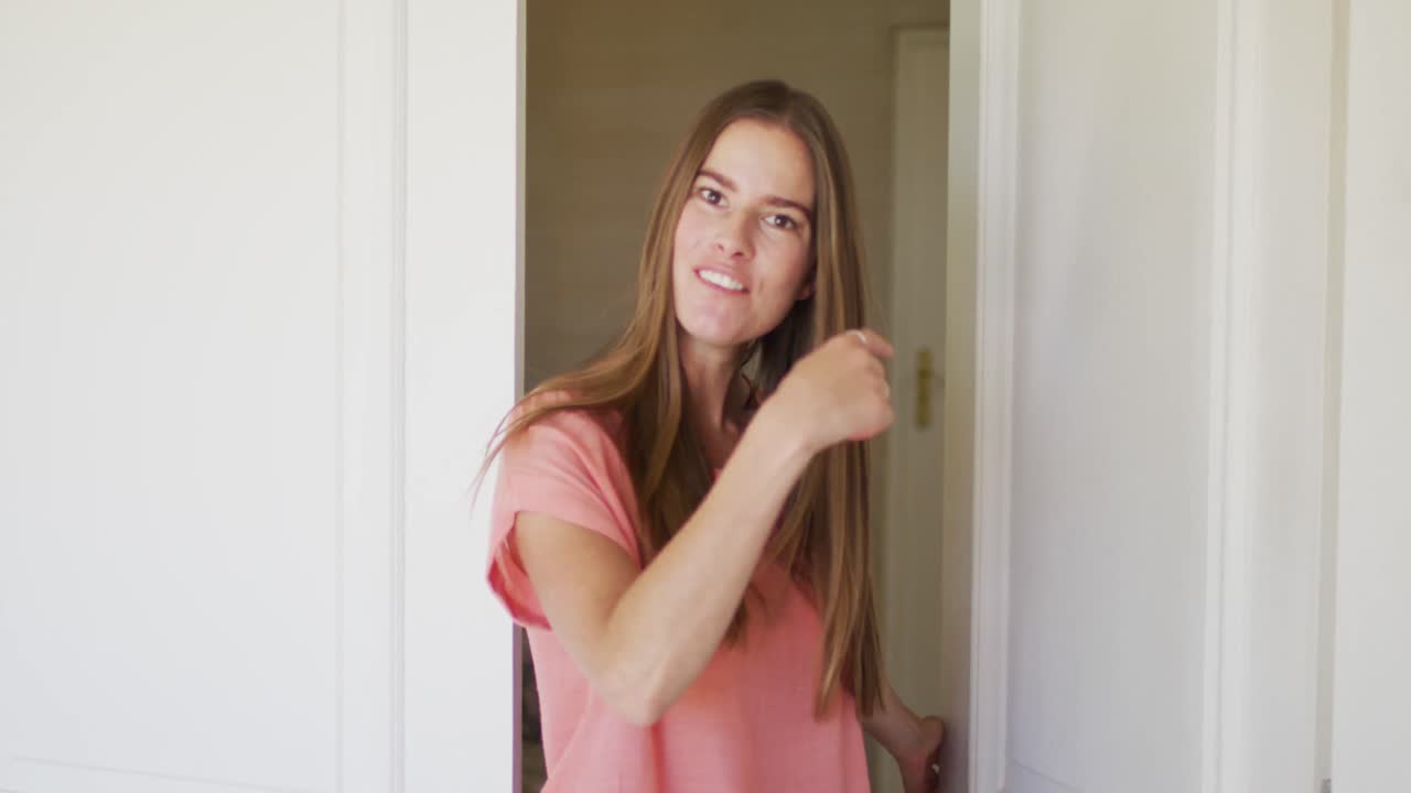 retrato de una mujer caucásica abriendo el frente de la casa para dar la bienvenida a la gente en