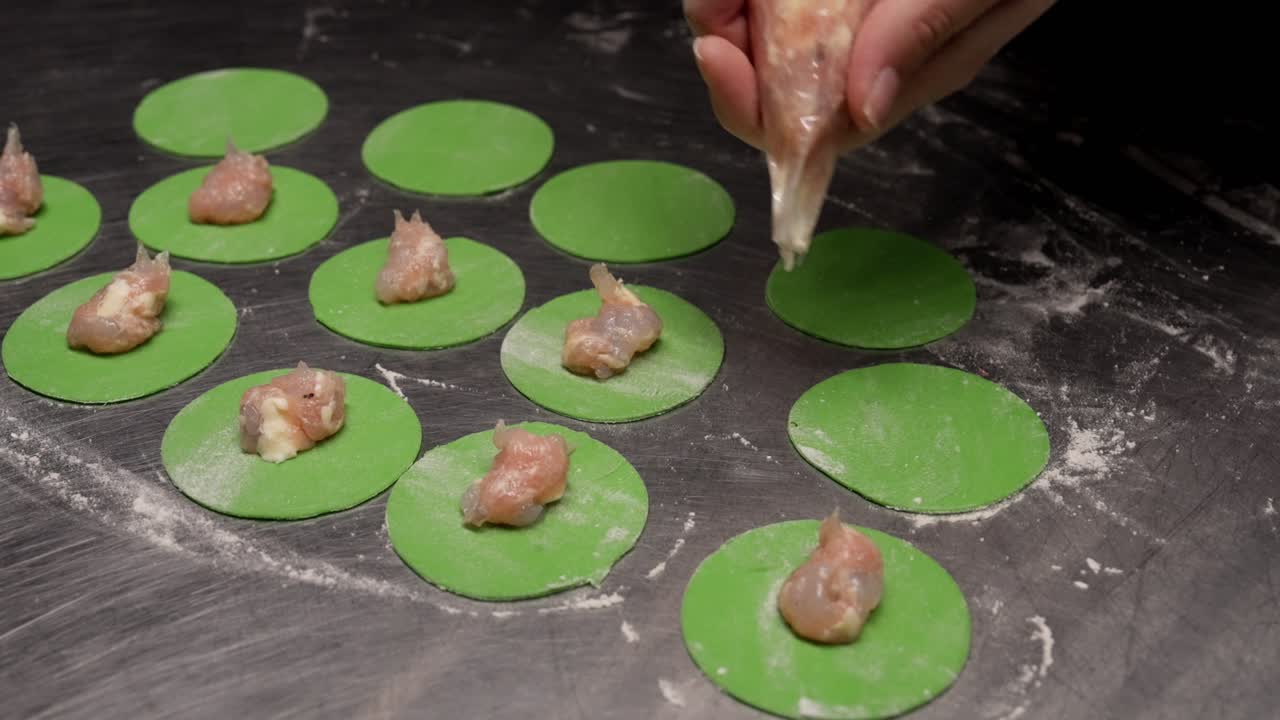 Hands Filling Green Dumpling Wrappers with Meat
