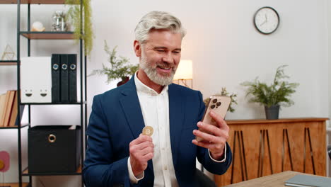 middleaged businessman checks crypto app on smartphone sees bitcoin rally gestures excited investor