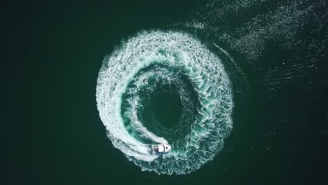 aerial bird view of a speedboat riding in a circle and making beautiful round path in the sea