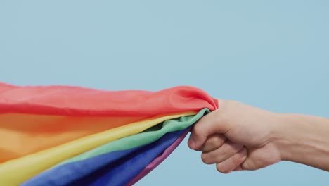 Video-Der-Hand-Eines-Kaukasischen-Mannes,-Der-Regenbogenstoff-Hält