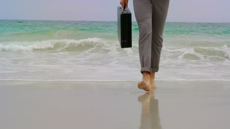 Sección-Baja-De-Un-Hombre-De-Negocios-Caminando-Descalzo-Con-Un-Maletín-En-La-Playa-4k