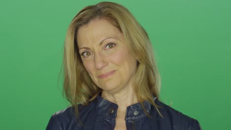 beautiful middle aged woman smiling, on a green screen studio background