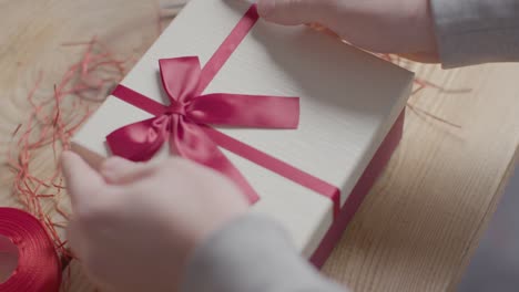 close up shot of man gift wrapping romantic valentines present of perfume in box on table 3