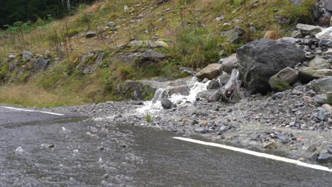 Runoff-from-heavy-rain-flowing-down-hillside-onto-roadway-in-Norway