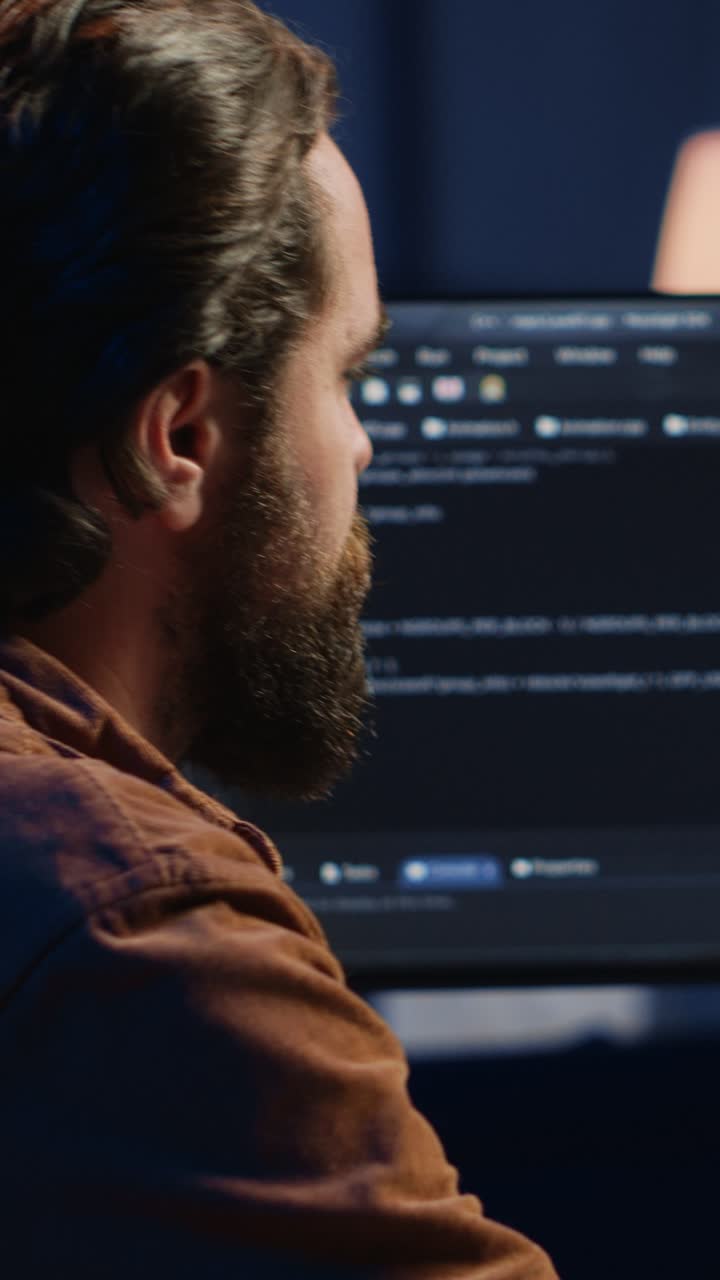 Focused Programmer Typing Code on Computer in Dark Office