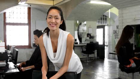 smiling female hairstylist leaning on chair
