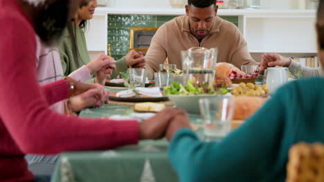 at christmas, diverse family holding hands, giving thanks around festive dinner table at home