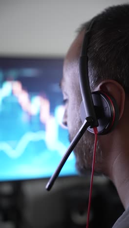 focused man analyzes data onscreen with headset in office setup